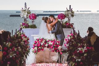 beso de novios en el altar con arco de flores