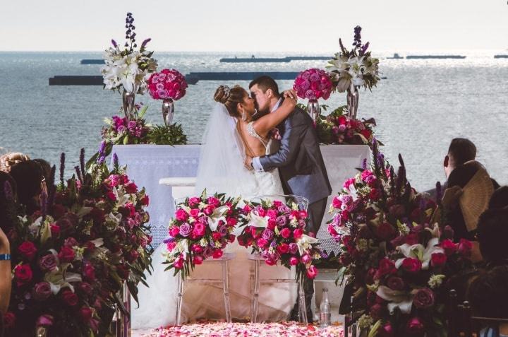 beso de novios en el altar con arco de flores