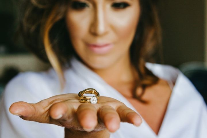 Novia con argolla de matrimonio y anillo de compromiso en mano