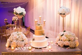 Mesa de pastel para boda con decoraciones de flores y candelabros