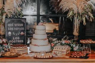 Mesa del pastel decorada con pizarras y postres para boda