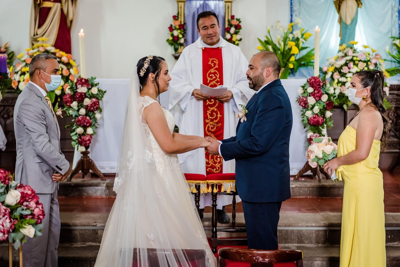 pareja en ceremonia de boda católica en el altar con testigos