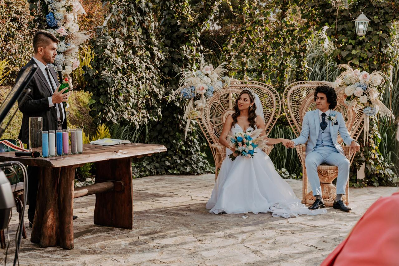 novios sentados en dos sillas y oficiante durante ceremonia nupcial