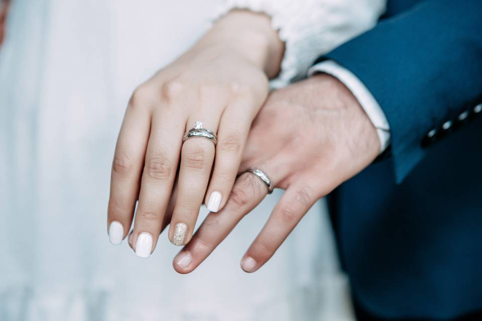 Foto de manos con argollas de matrimonio en oro blanco