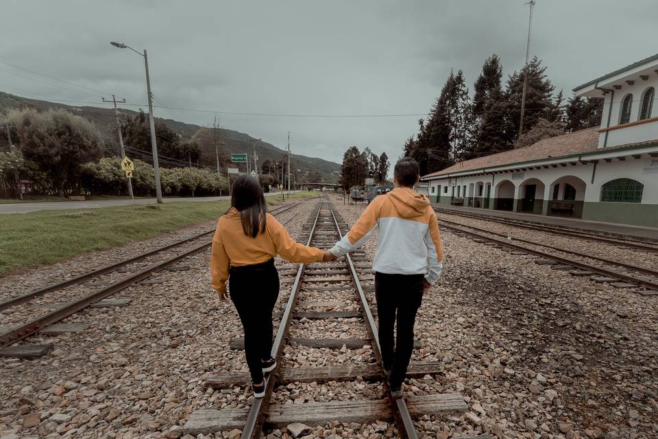 pareja caminando de la mano en riel de estación de tren en sesión de fotos de preboda