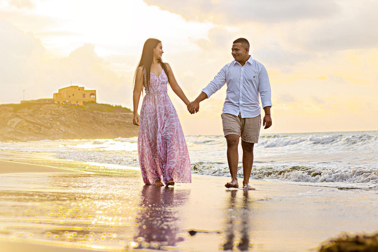 Pareja en preboda caminando por la playa al atardecer