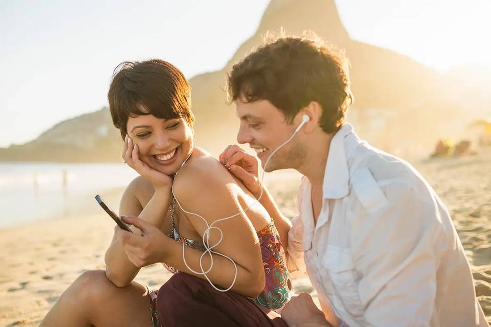 pareja que escucha música en la playa