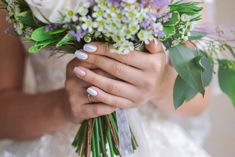 Manos sostienen ramo de novia con manicure