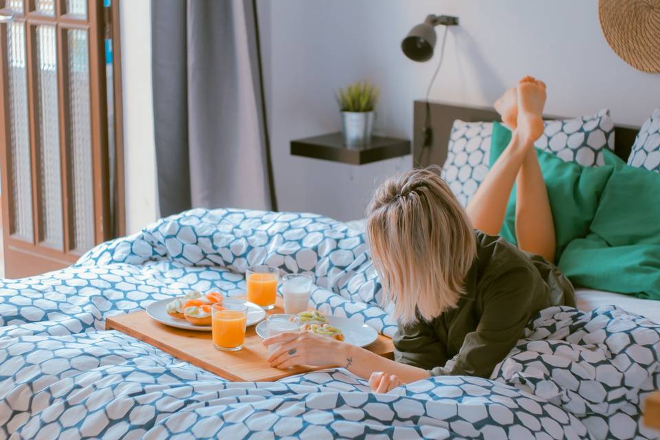mujer en la cama con desayuno en una bandeja - desayunos para sorprender a tu pareja