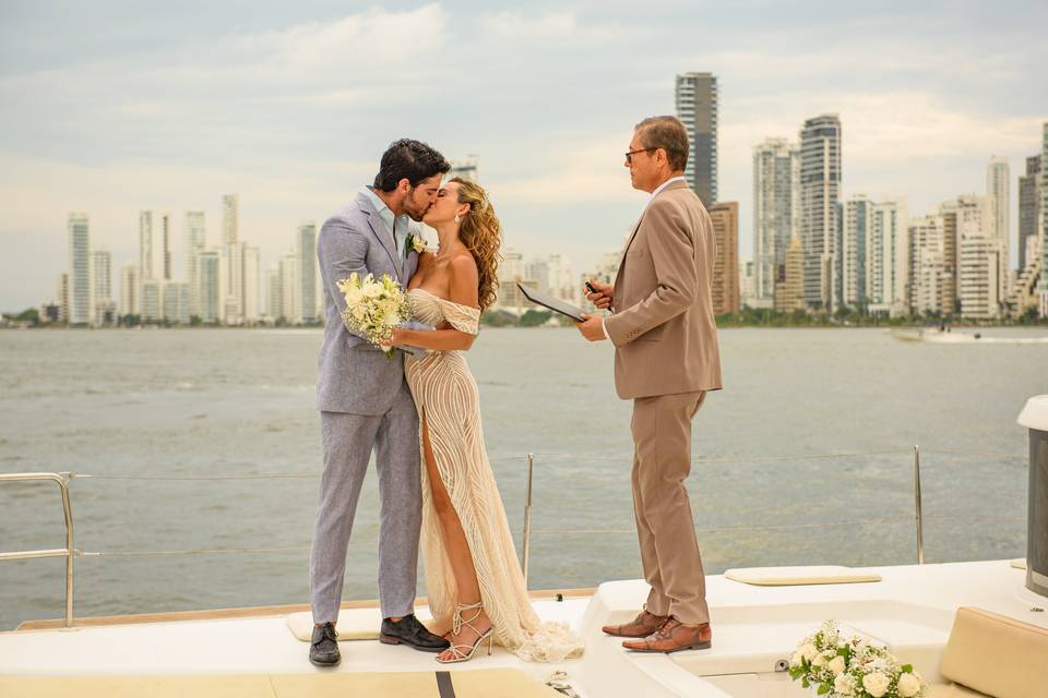 Novios besándose frente a una ciudad con mar