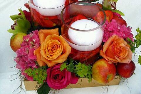 Rosas, fruta y velas en agua.