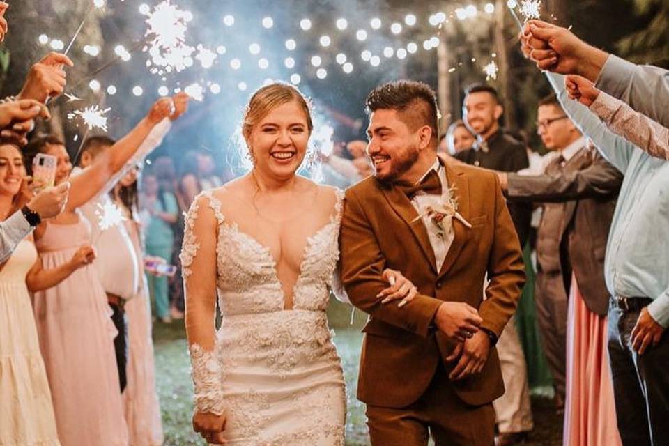 Pareja sonriendo y caminando entre sus invitados