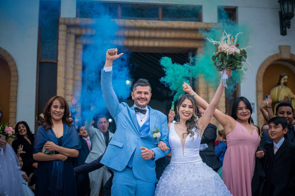 Pareja saliendo de la iglesia con humo de colores