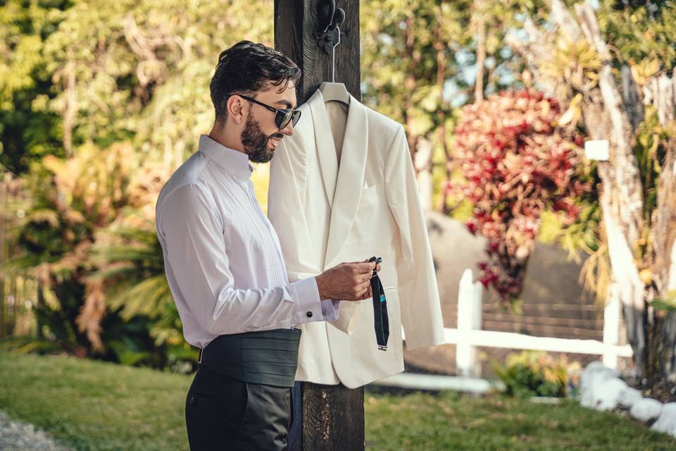 Novio enfrente de la ventana con el saco colgando