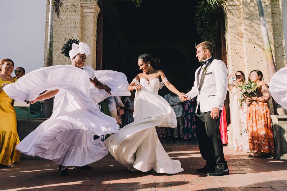 Novios con bailarinas afuera de la iglesia