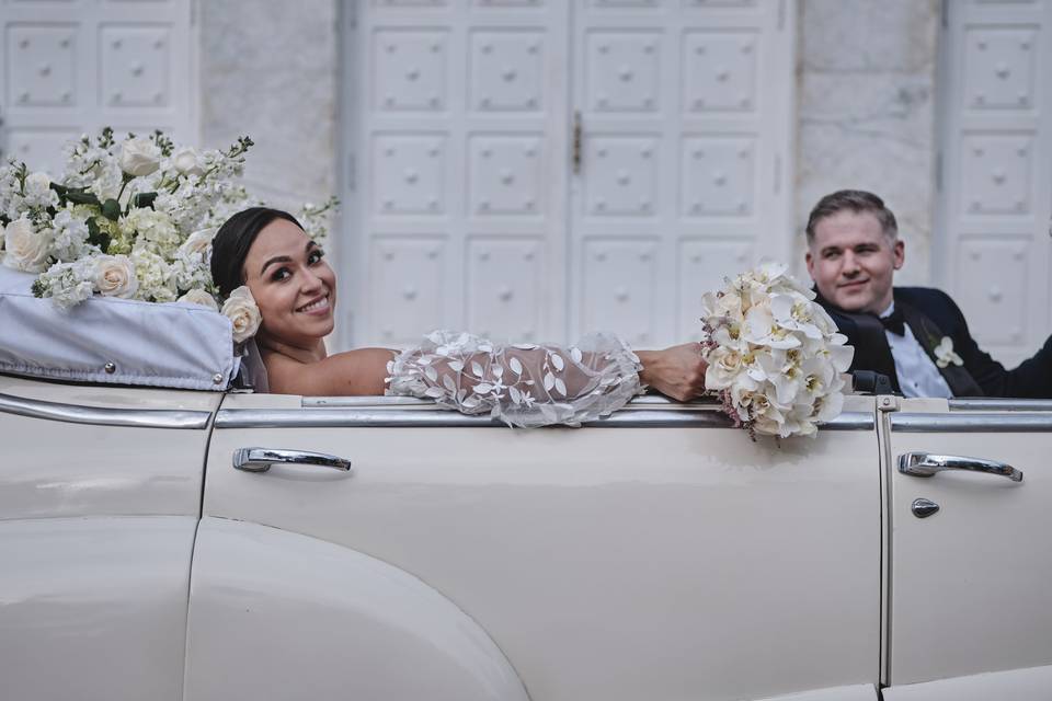 Recién casados en un carro convertible blanco