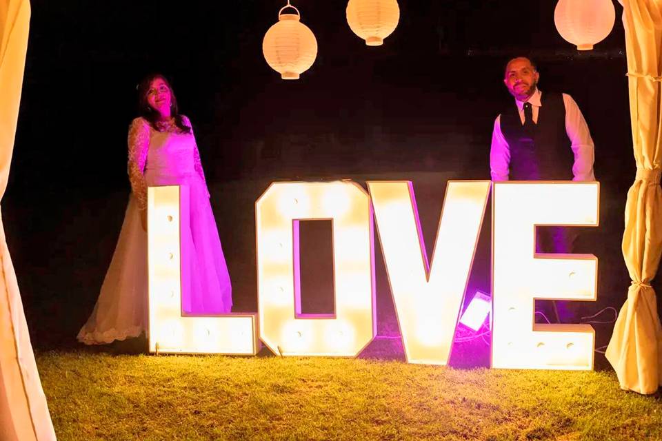 Novios posando con letras gigantes iluminadas