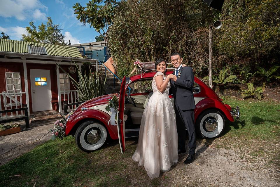 Novios posando frente a un Volkswagen