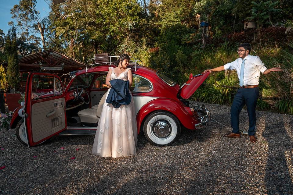 Novio abriendo la cajuela del Volkswagen y novia sujetando el saco