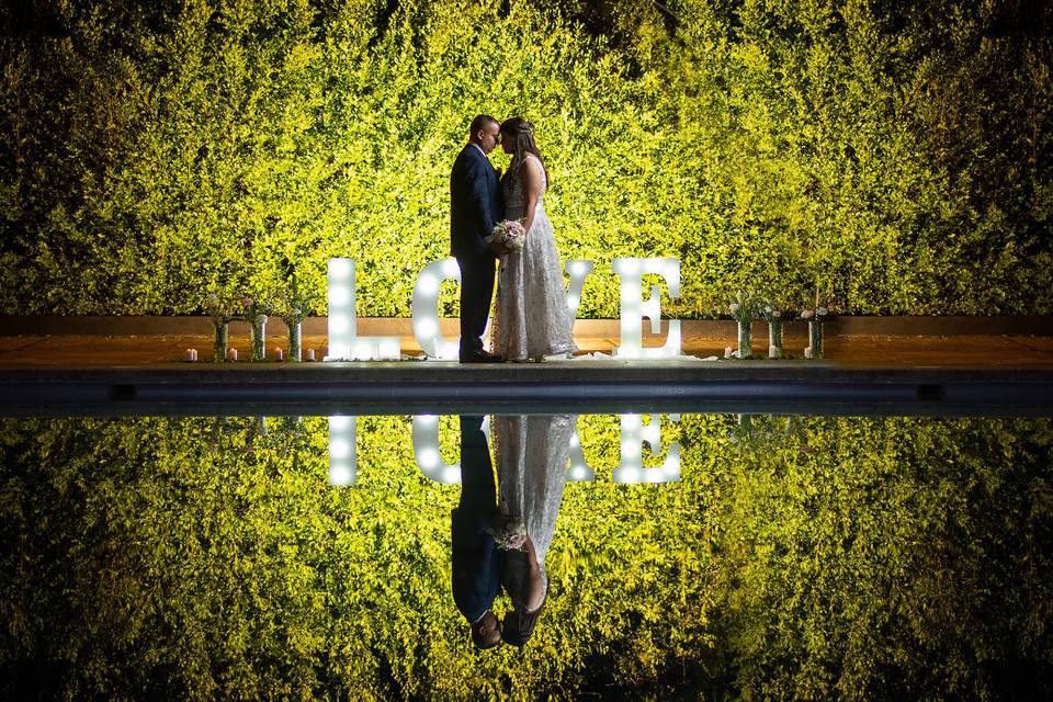 Novios besándose frente a un lago iluminado