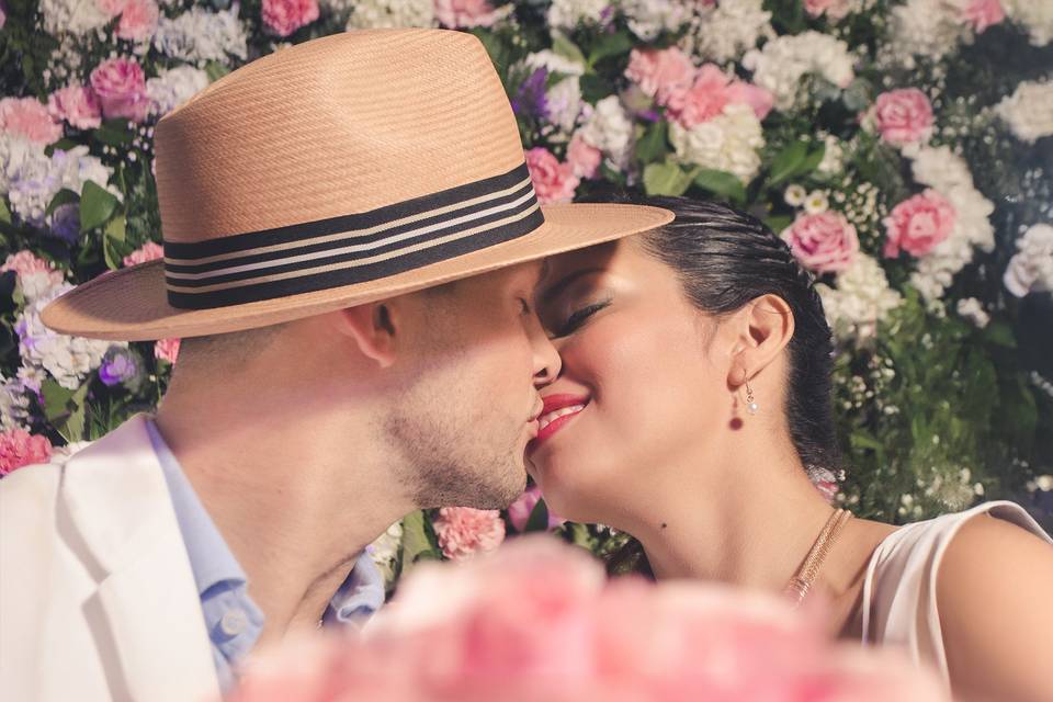 Novios dándose un beso rodeados de flores