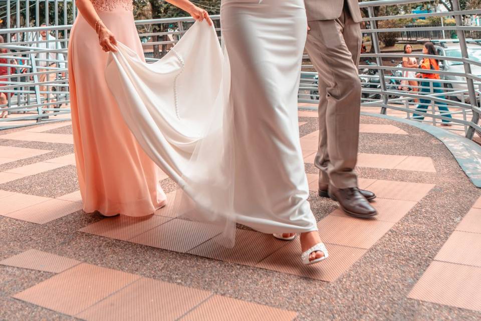 Novia caminando con su ramo mientras le sostienen la cola del vestido