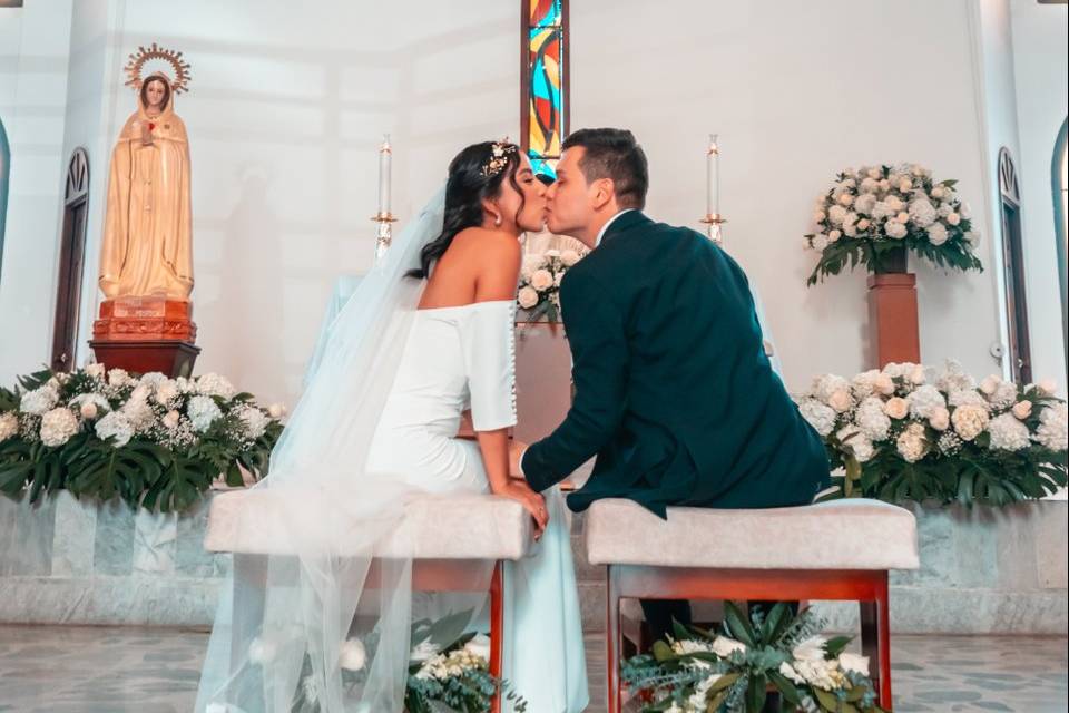 Novios dándose un beso en su ceremonia religiosa