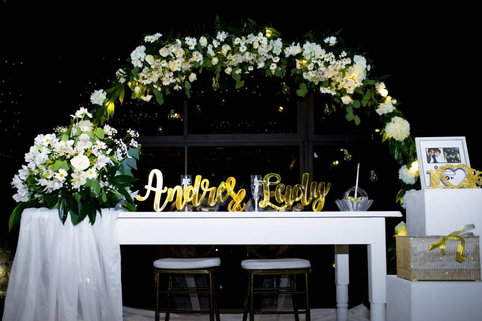 Arco de flores blancas en mesa de novios