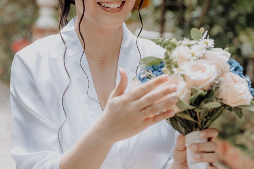 Novia sonriendo, viendo su ramo de flores