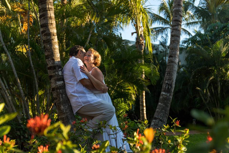 Novios recargados en una palmera