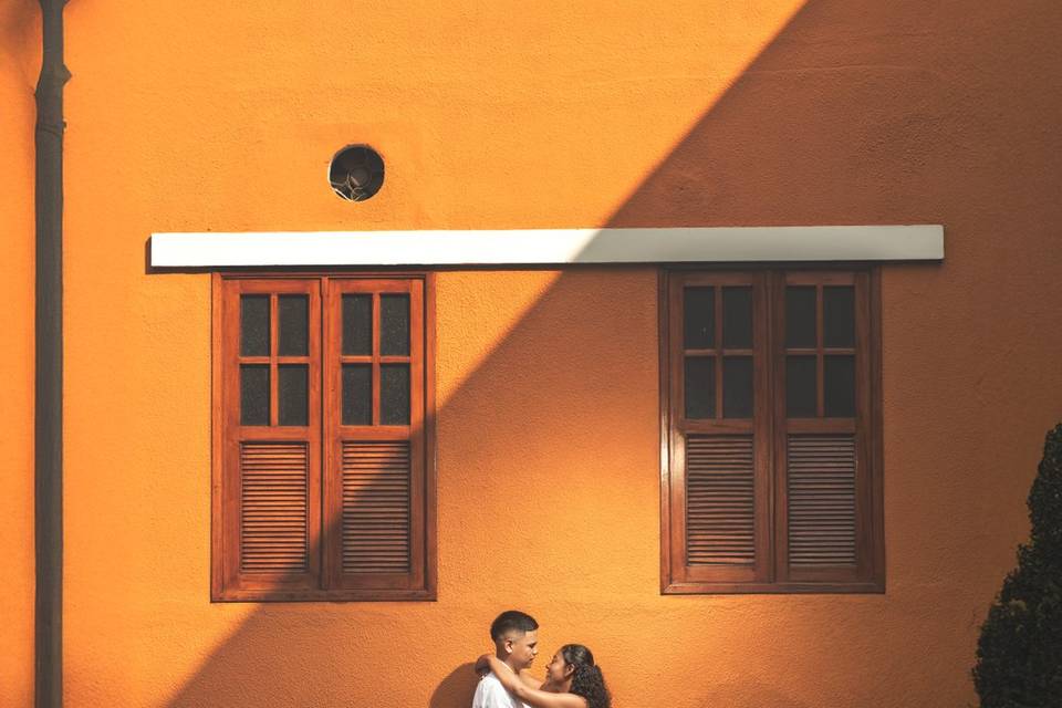 Pareja posando frente a una casa naranja