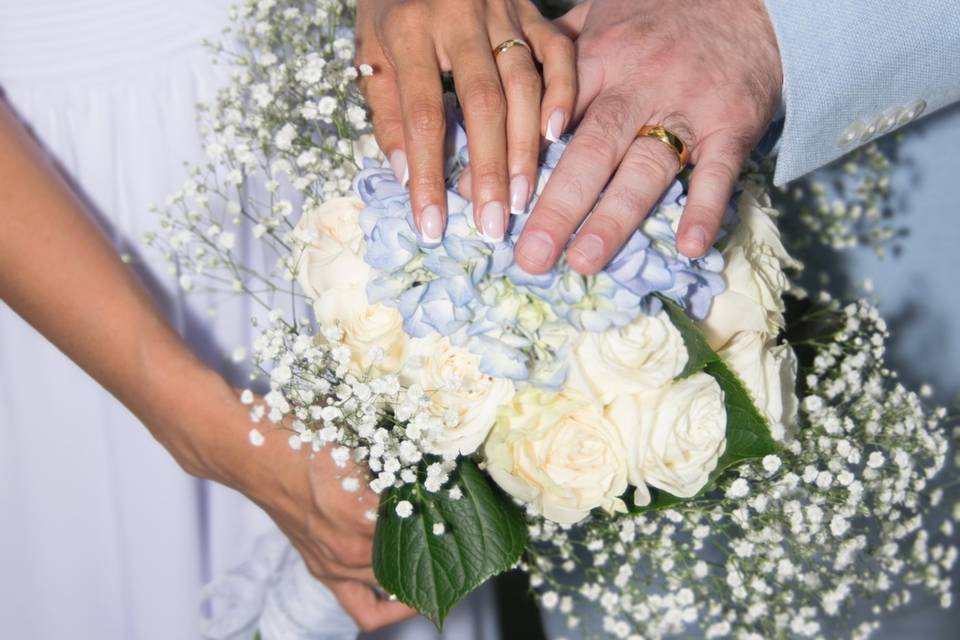 Manos de los recién casados sobre el ramo