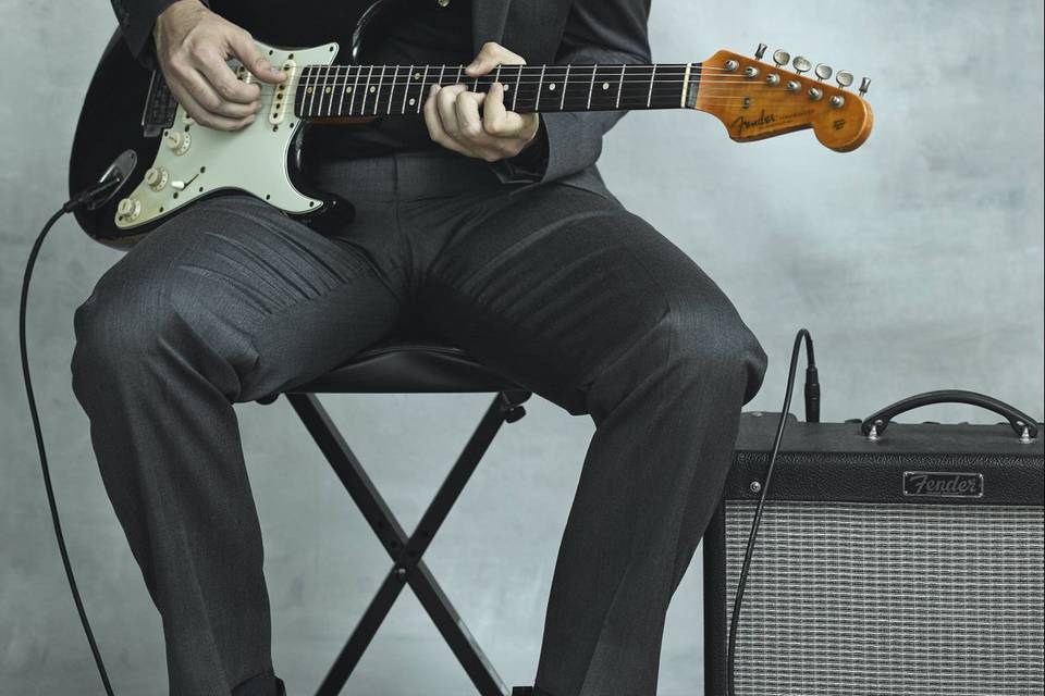 Músico sentado tocando la guitarra eléctrica