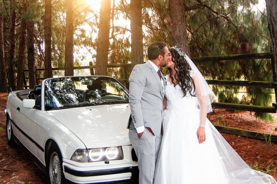 Novios besándose frente a un auto blanco
